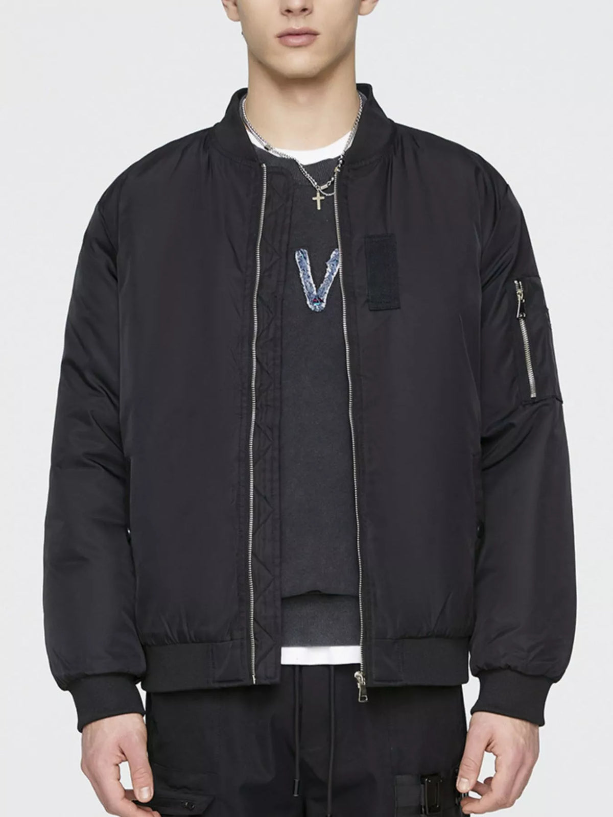 Black bomber jacket shown open from the front on a model; layered shirts, trousers and necklaces are not included.