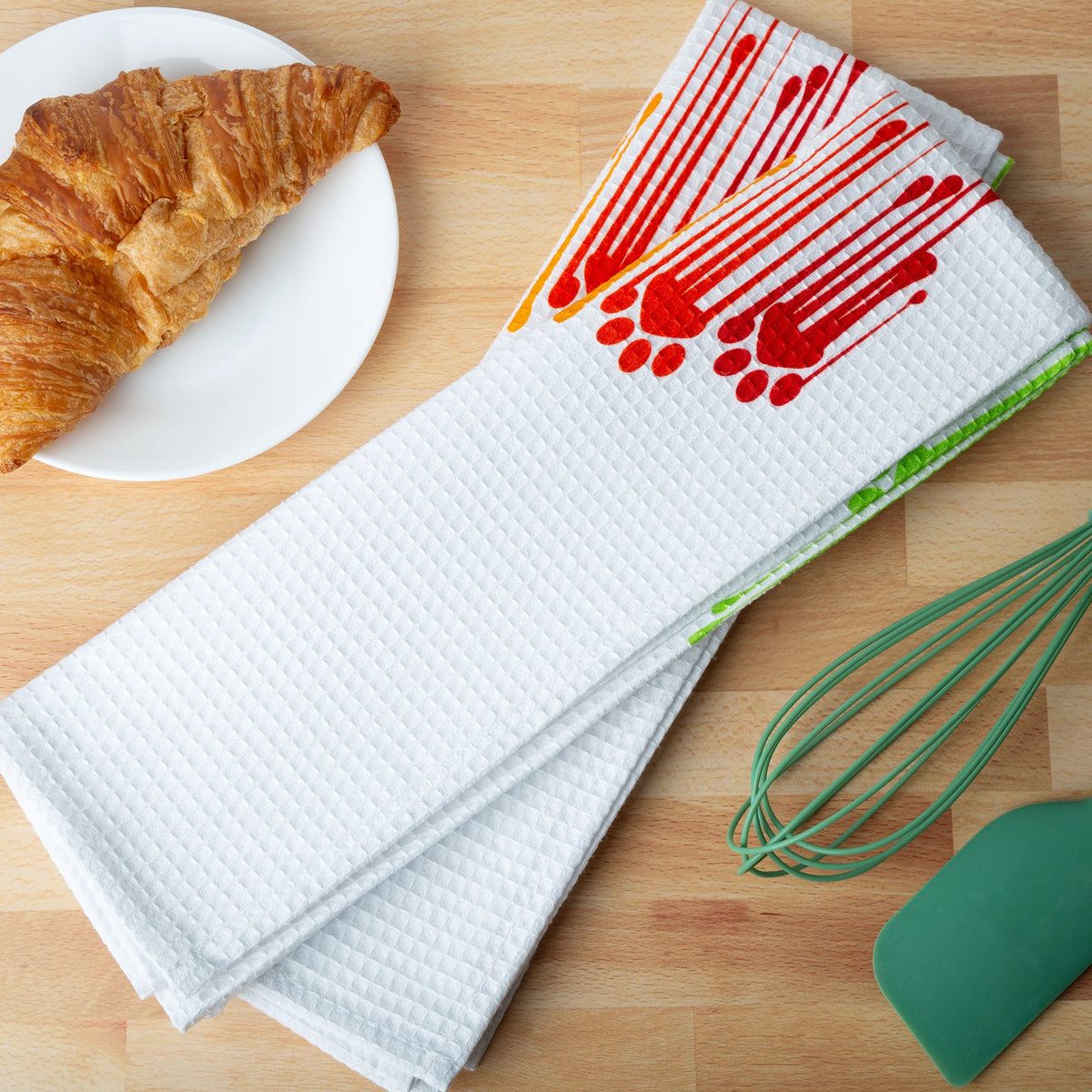 Rainbow Paws kitchen towels on a counter; food and utensils are styling props.