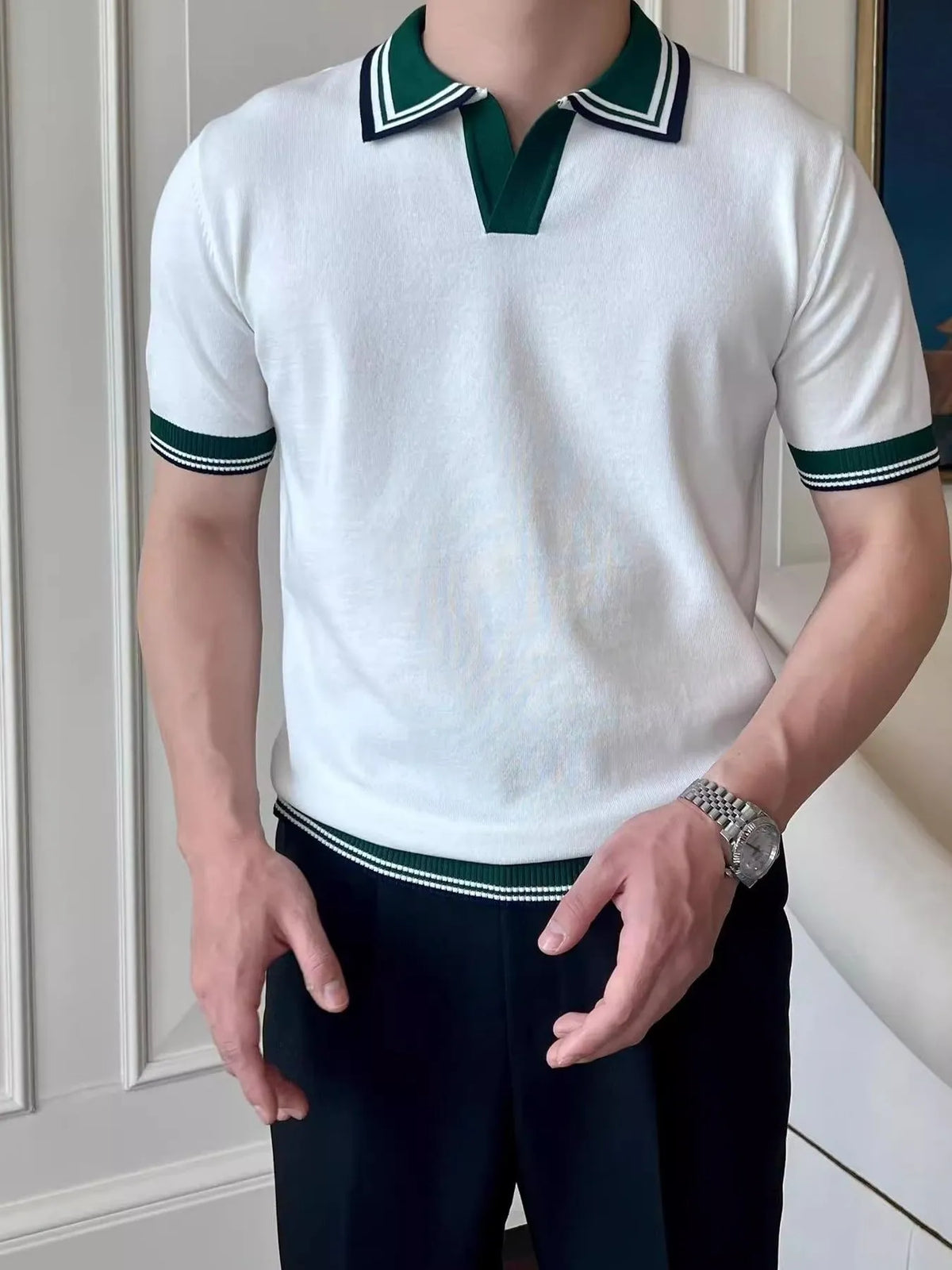 White short-sleeve knit polo with dark green and navy striped trim, worn on a model. Shirt only.