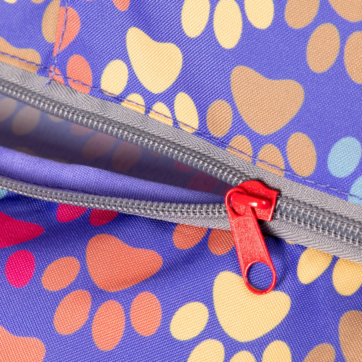 Close view of the Diagonal Paws multicolor fabric and red zipper pull.