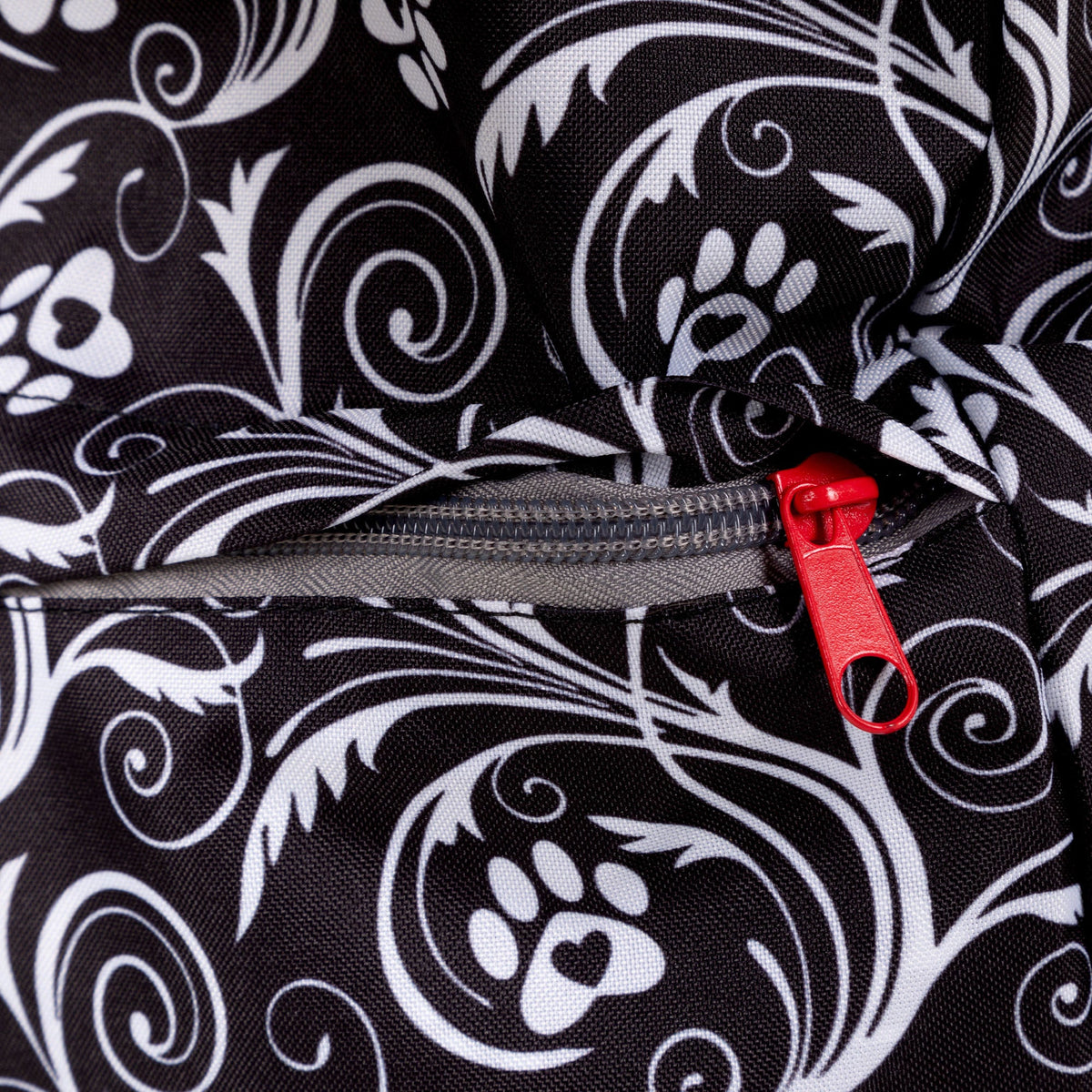 Close view of the Flourish Paws backpack's black-and-white fabric and red zipper pull.
