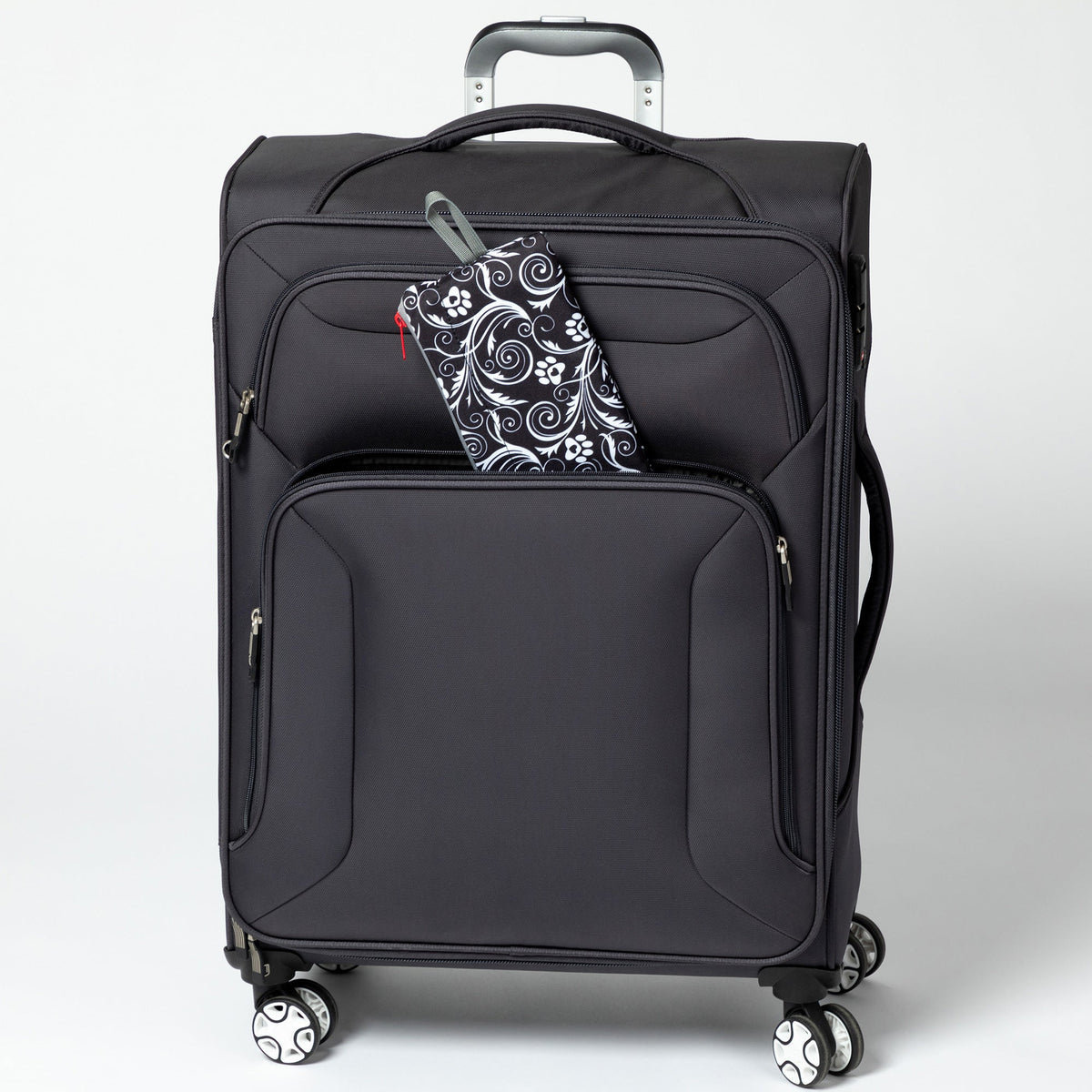 Folded Flourish Paws backpack beside a rolling suitcase; suitcase not included.