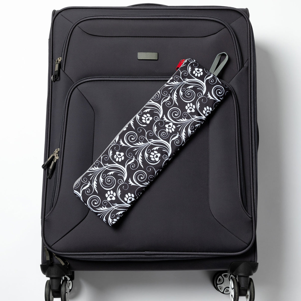 Folded Flourish Paws backpack displayed on a rolling suitcase; suitcase not included.