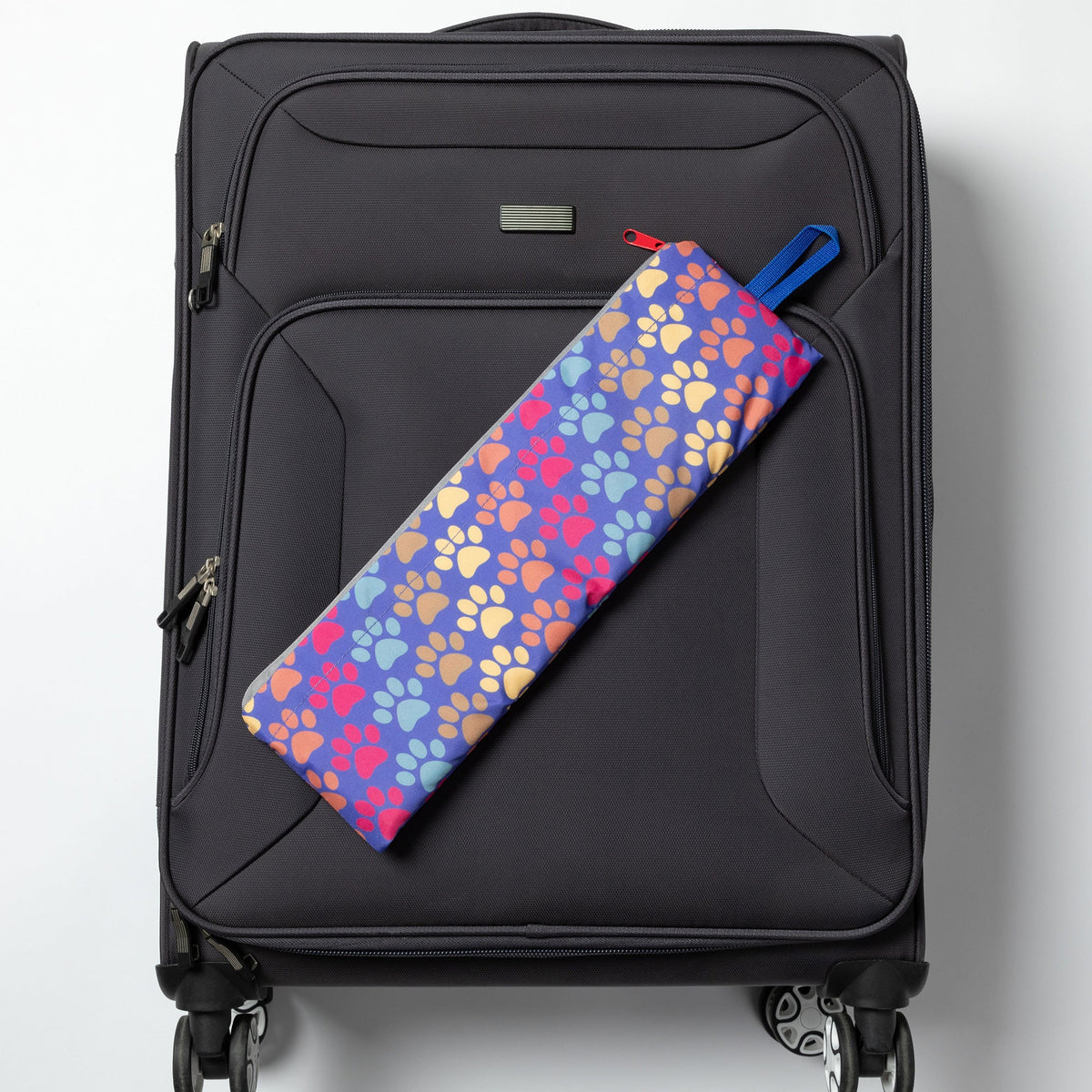 Folded Diagonal Paws backpack displayed on a rolling suitcase; suitcase not included.