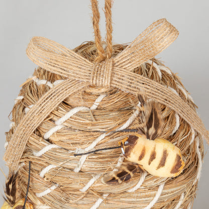Close-up of the decorative beehive-shaped birdhouse's ribbon and faux bee.