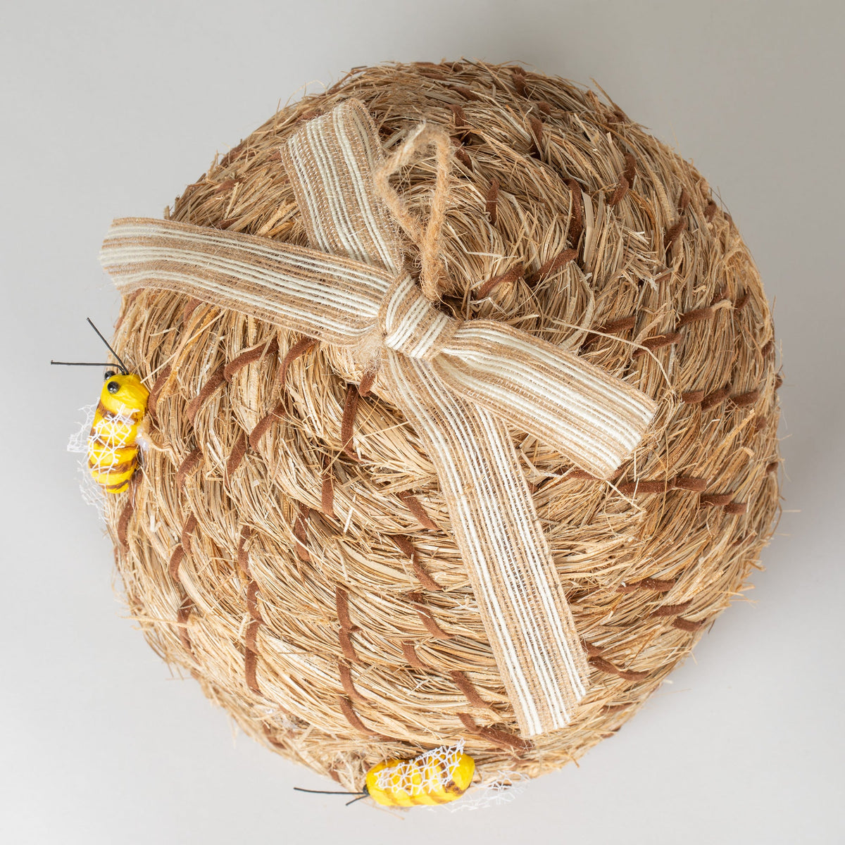 Bottom view of the decorative beehive-shaped birdhouse with ribbon and faux bees.