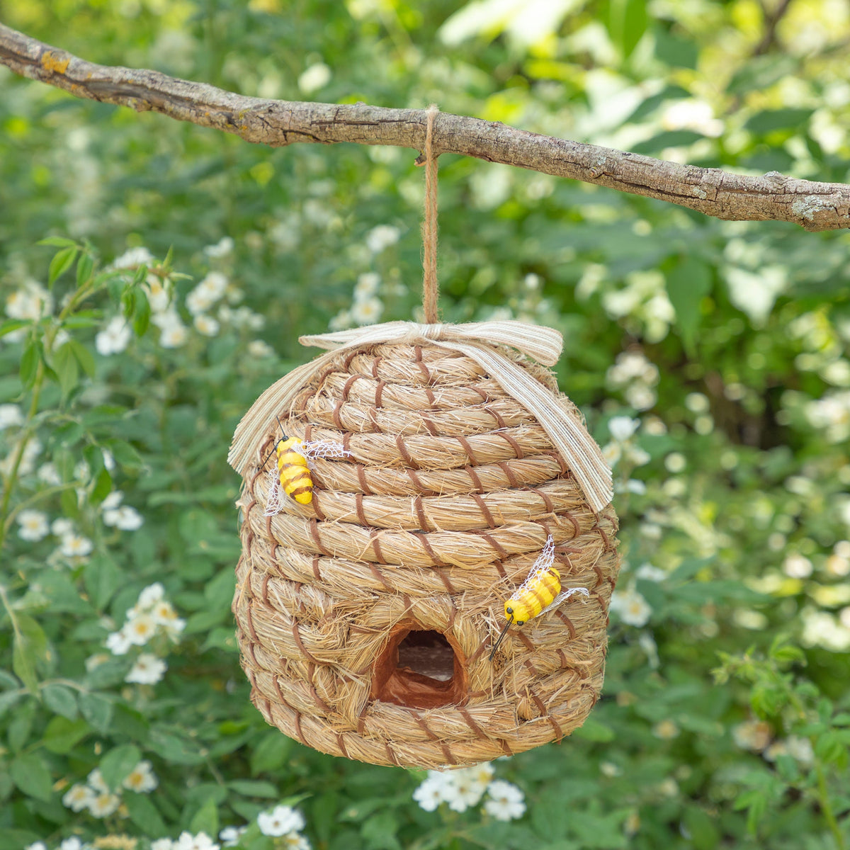 Decorative beehive-shaped birdhouse with faux bees hanging from a branch.