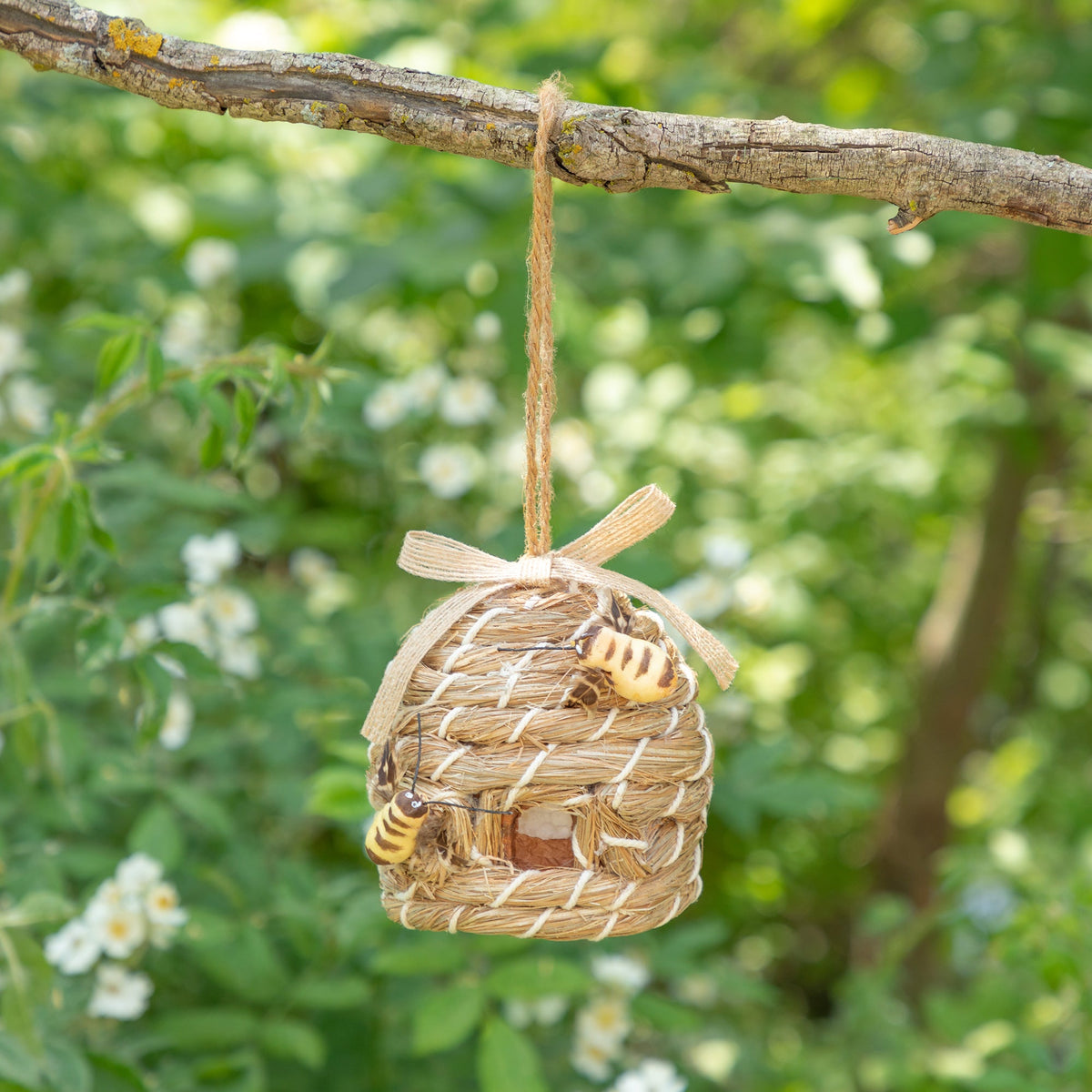 Decorative beehive-shaped birdhouse with faux bees hanging from a branch.