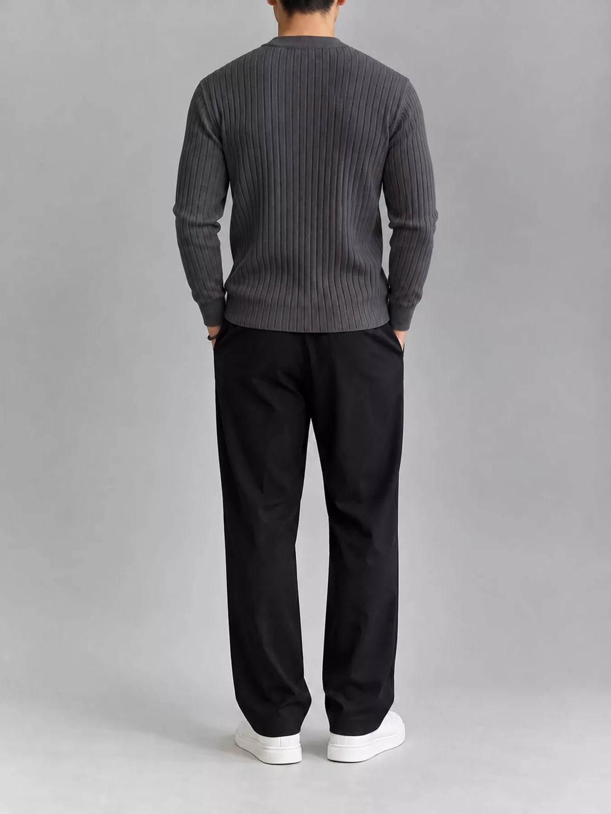 Dark gray ribbed knit top, modelled rear view. Trousers and shoes are not included.