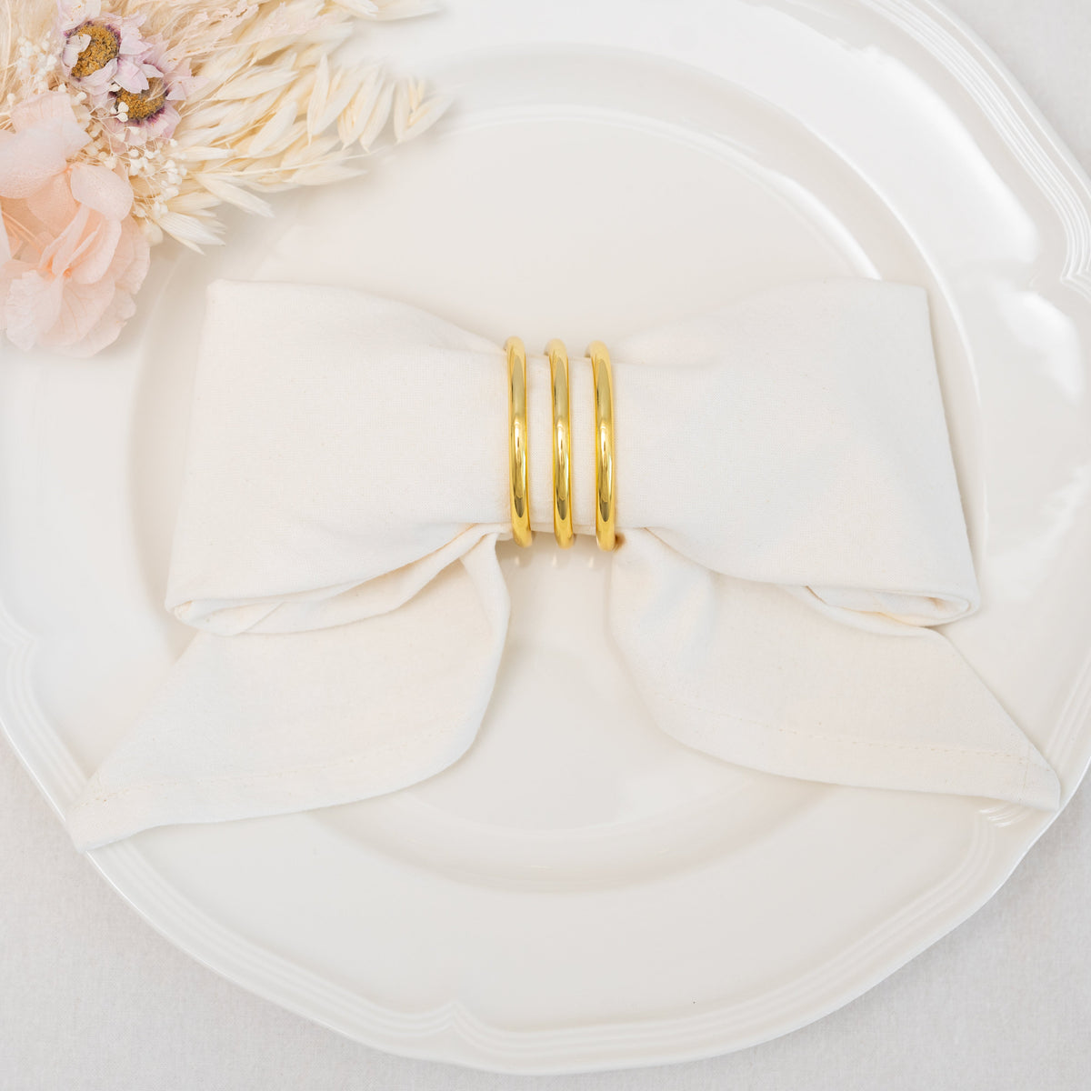 White flour-sack cotton napkin folded on a dinner plate with a decorative ring