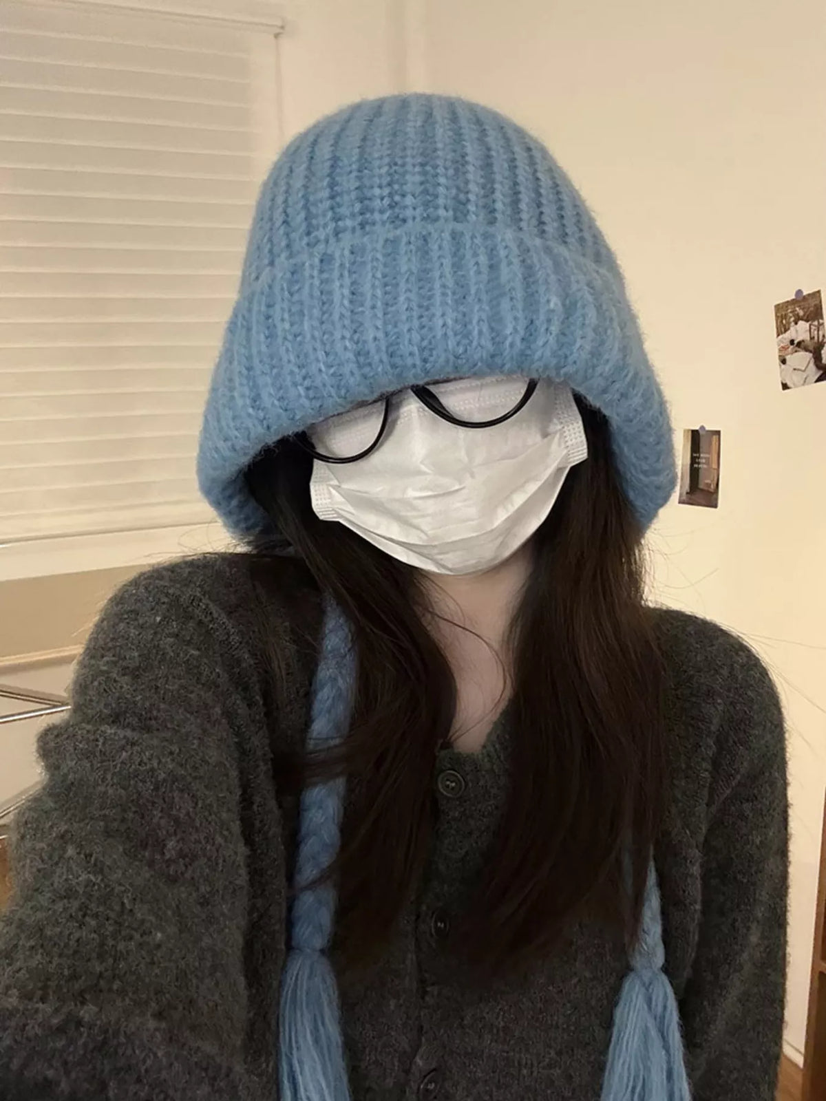 Blue ribbed knit beanie with long braided ties, worn from the front
