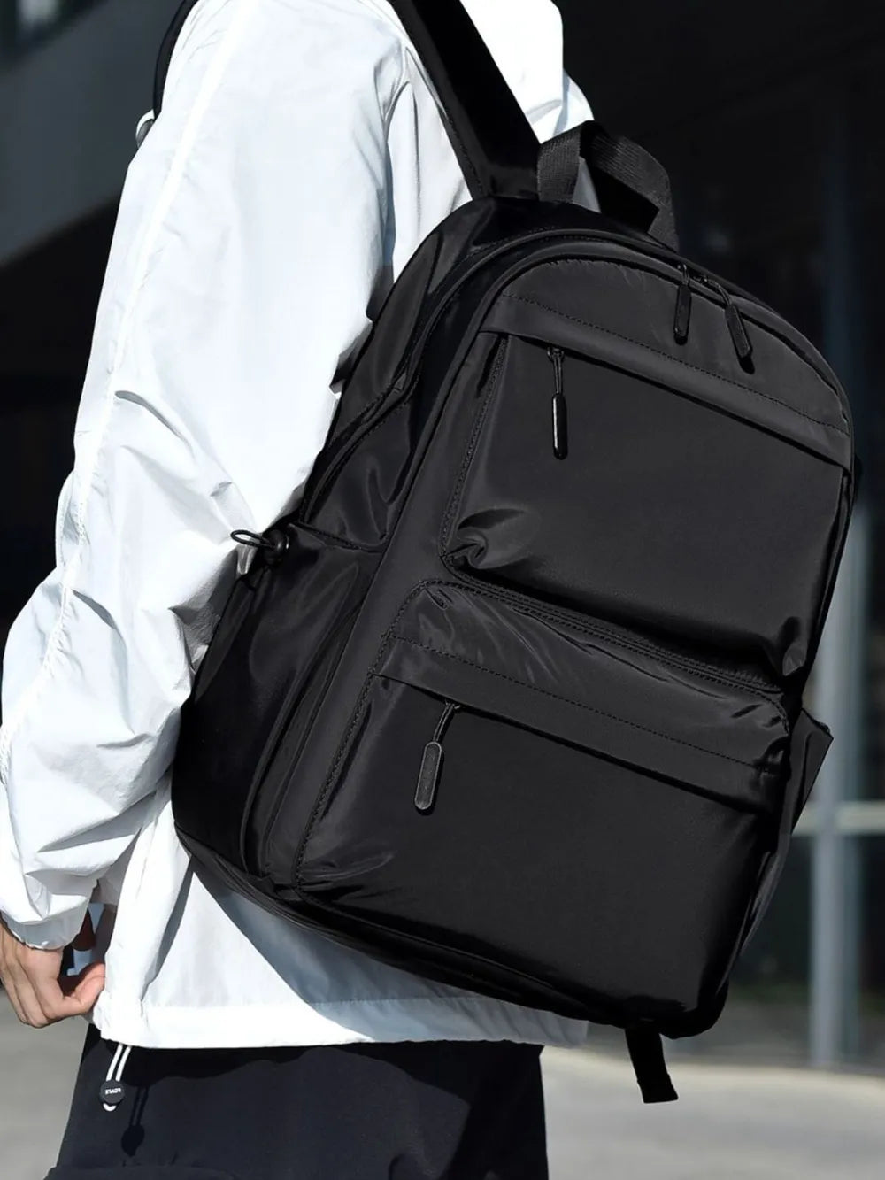 Black backpack worn over a white long-sleeve top; clothing not included