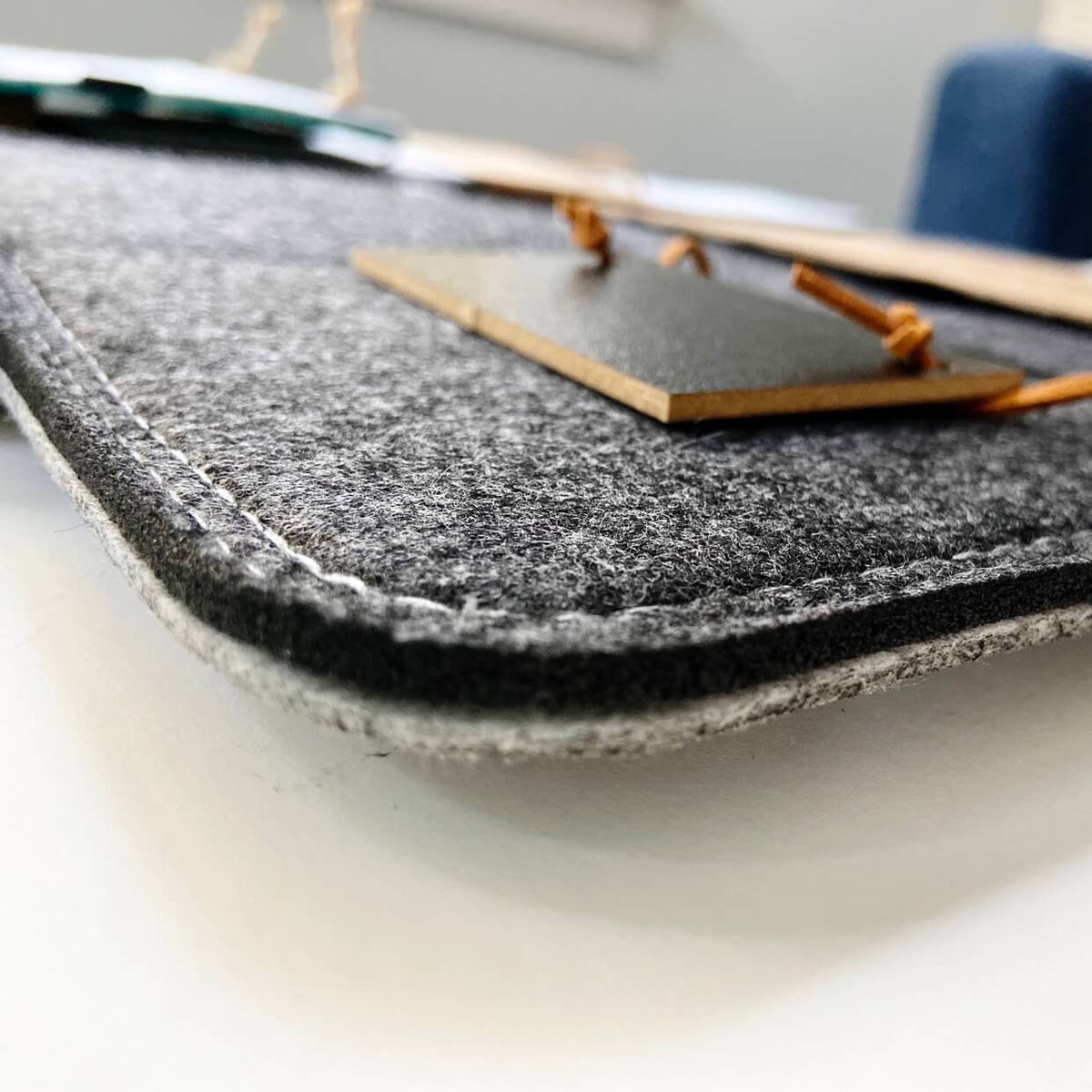 Macro view of the organizer's charcoal felt surface, stitched edge and brown cord.