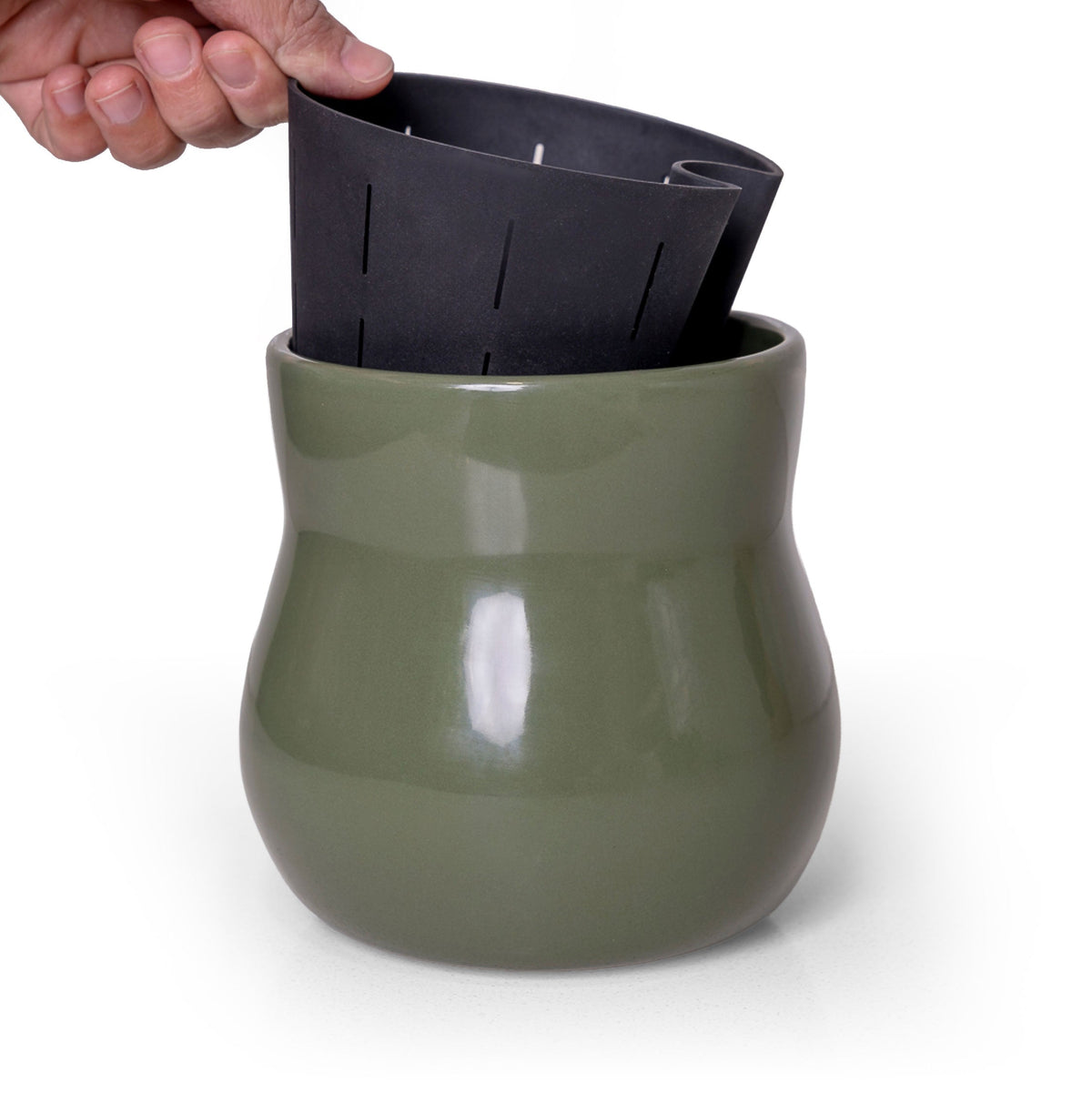Hand lifting the removable liner from the Forest Green ceramic planter; plant and props are not included.