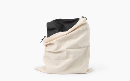 Natural cotton drawstring storage bag with a black handbag inside.