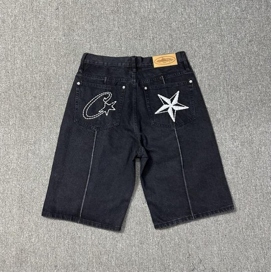 Back view of dark denim shorts with contrasting embroidered designs on two back pockets.