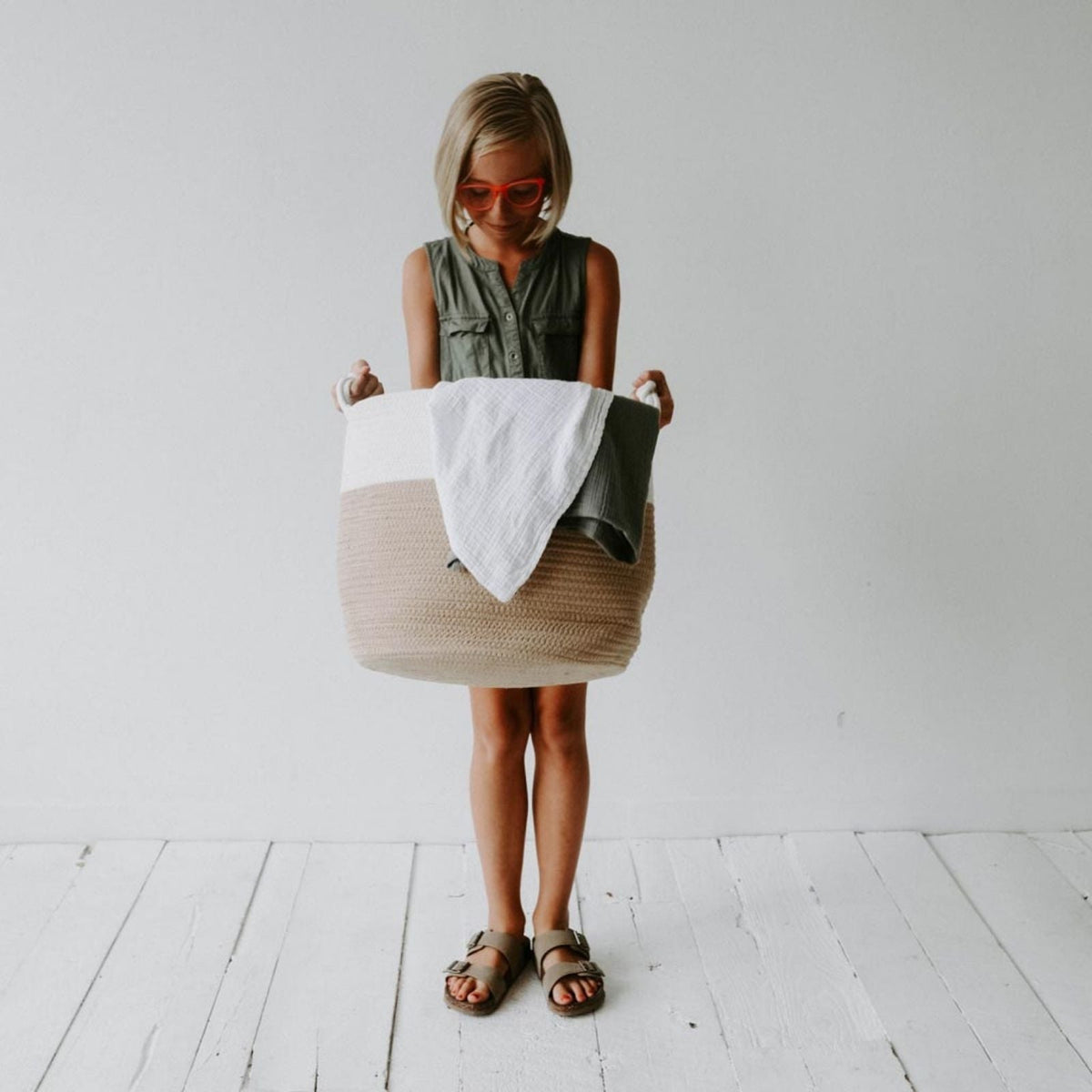Child holding the cream and beige rope basket with blankets; blankets are not included.