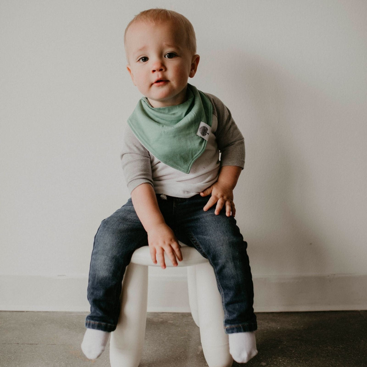 Baby wearing the green bib from the Estes eight-bib set; clothing and stool are not included.