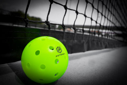 Neon Potenza TBX outdoor pickleball beside a court net; net not included
