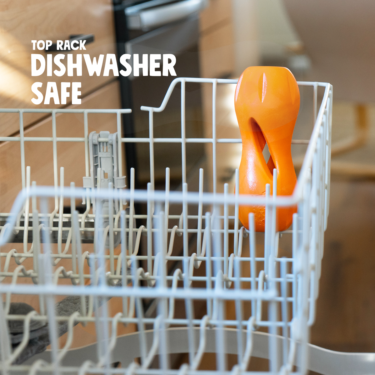Tangerine West Paw Qwizl toys in a dishwasher rack; graphic says top-rack dishwasher safe.