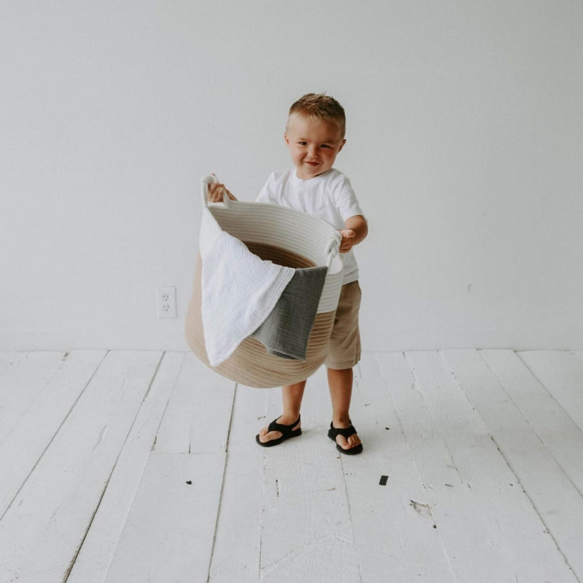 Child carrying the cream and beige rope basket with blankets; blankets are not included.