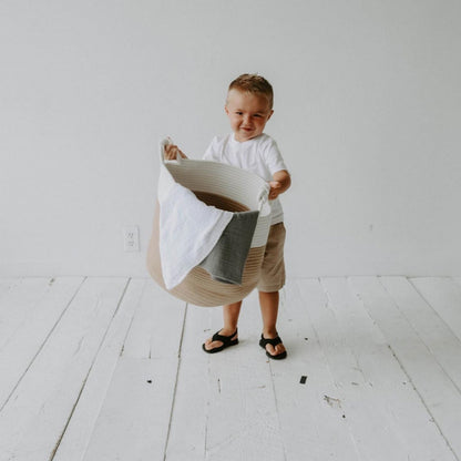 Child carrying the cream and beige rope basket with blankets; blankets are not included.