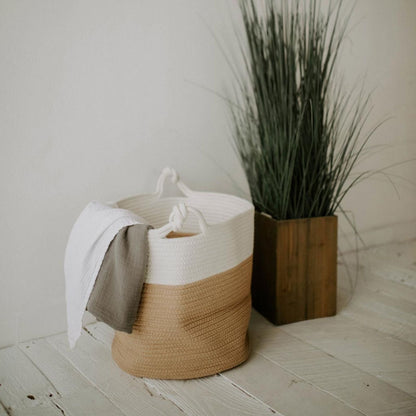 Rope basket holding blankets beside a potted plant; blankets and plant are not included.