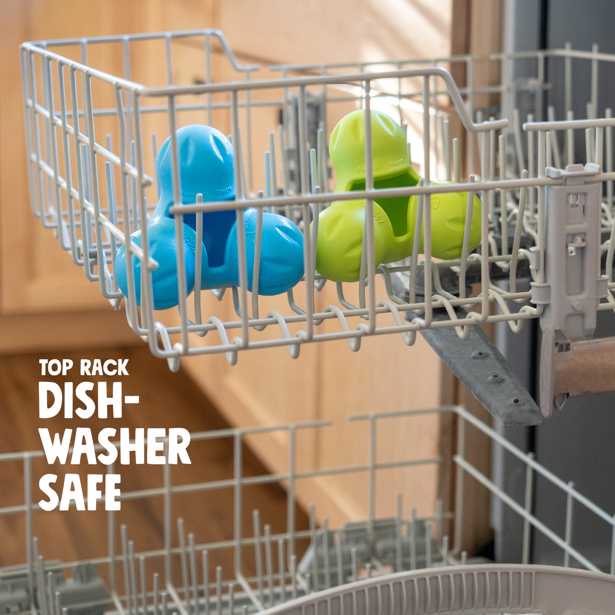 Aqua Blue, Granny Smith green and Tangerine West Paw Tux treat toys in the top rack of a dishwasher.