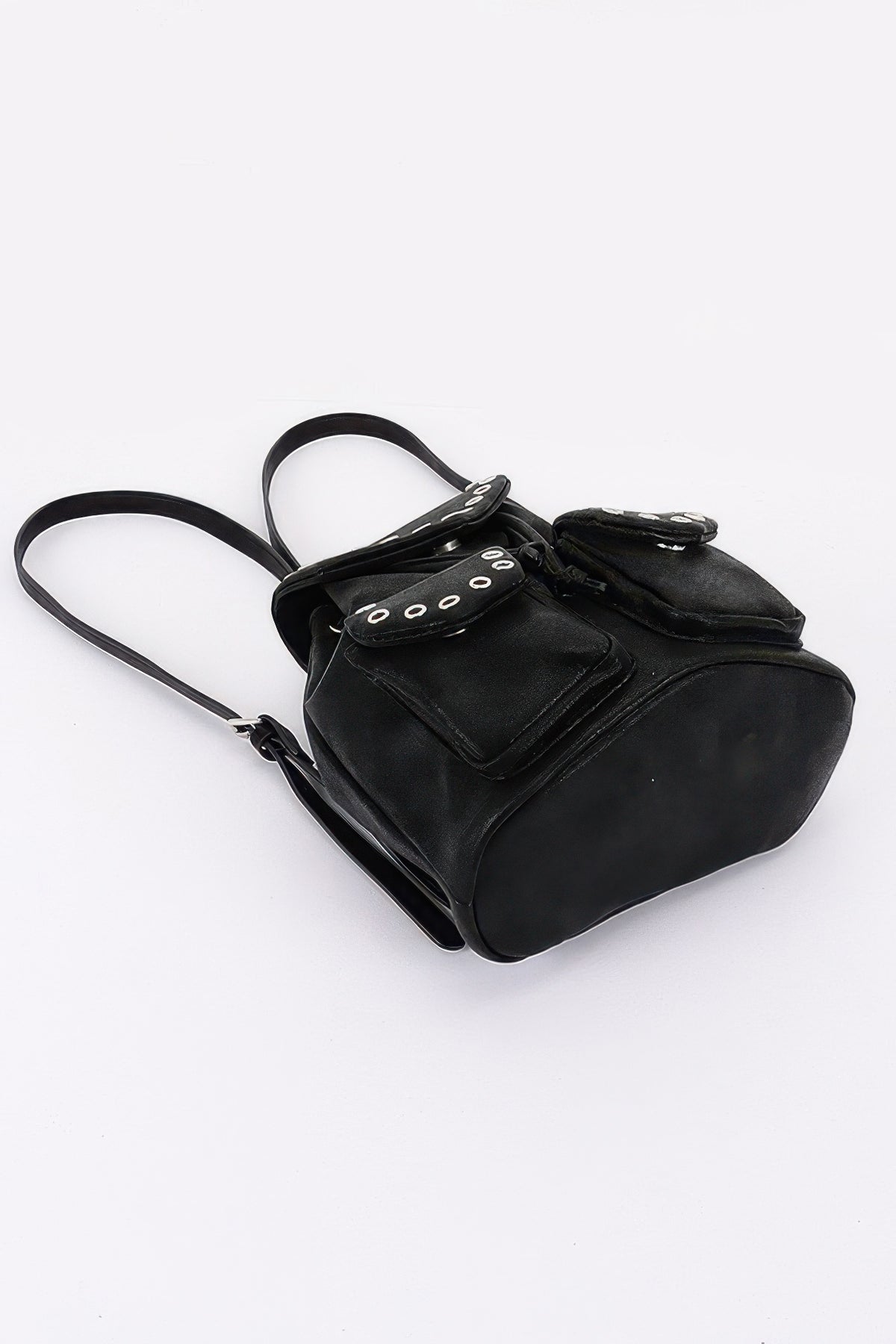 Black faux-leather backpack lying on its side, showing the flat base and shoulder straps.