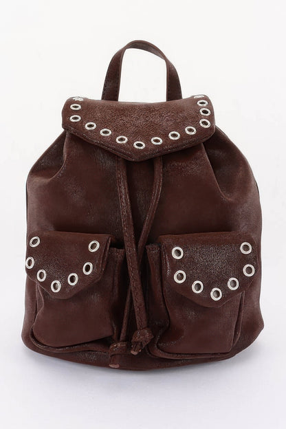 Brown faux-leather backpack, front view with curved flap, metal eyelets and two front pockets.