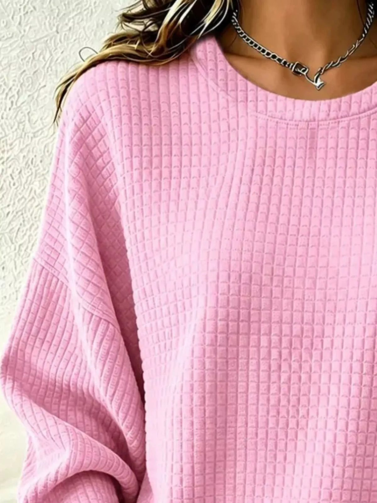 Close-up of the Pink sweatshirt's crew neckline, waffle-knit texture and sleeve.