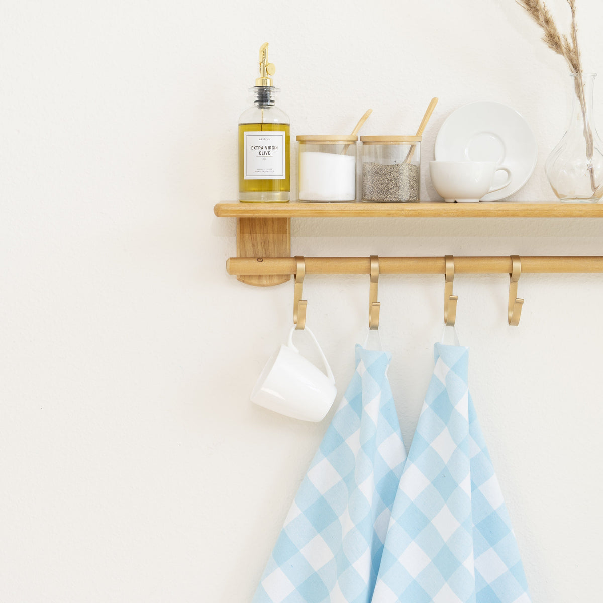 Aqua-and-white plaid kitchen towels hanging below a kitchen shelf; shelf and utensils not included.