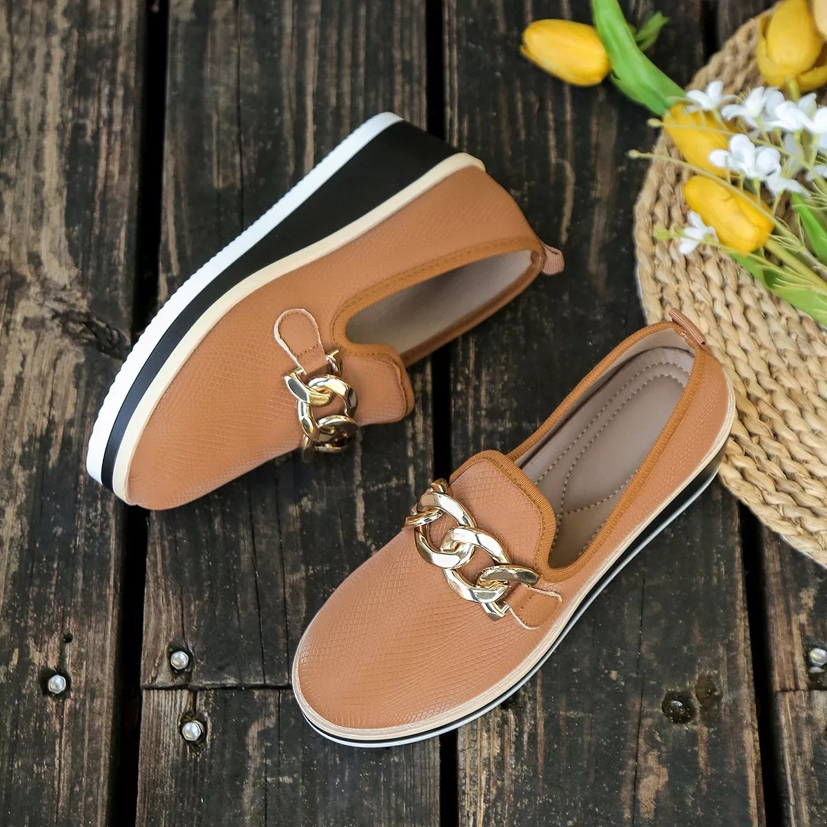 Brown loafers displayed on a wooden surface beside flowers; one selected pair is included.