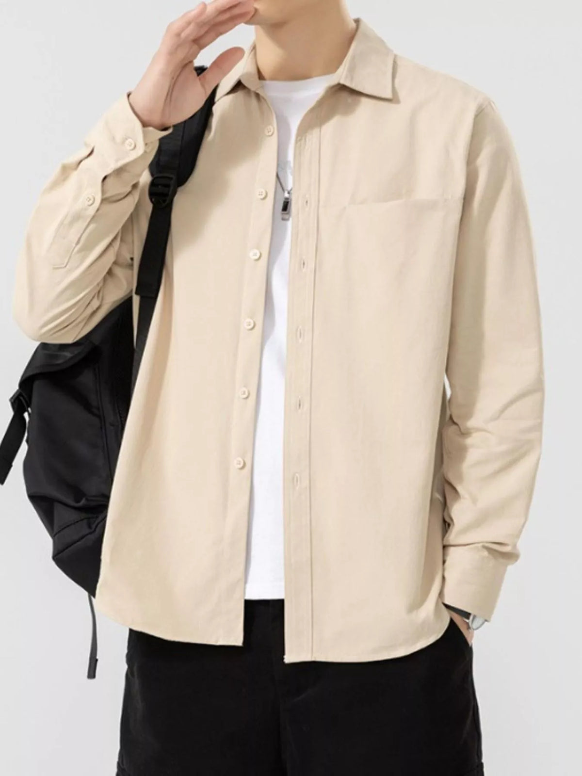 Beige button-front shirt with the model's hand raised, showing the cuff; underlayer and bag are not included.