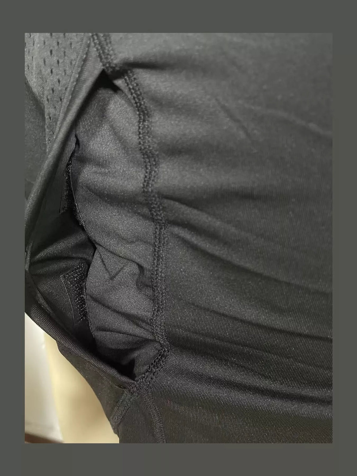 Close-up of dark fabric, a mesh side panel and a stitched seam.