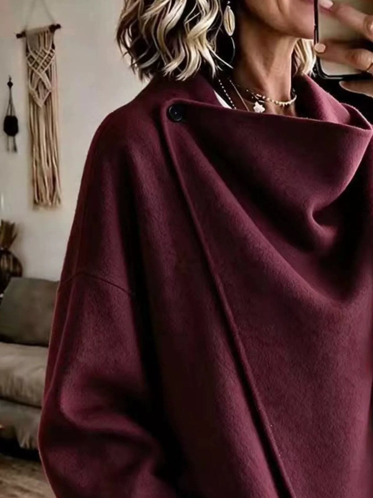 Burgundy asymmetric cowl-neck cape, close-up of the draped neckline and button detail