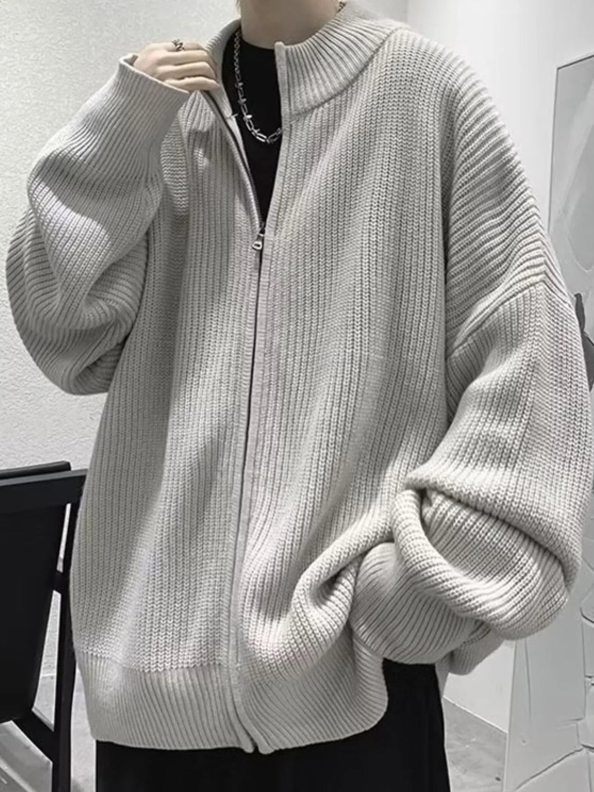 Gray oversized ribbed cardigan partly zipped, showing the long sleeves, stand collar and ribbed hem.