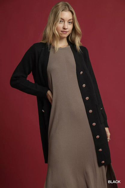 Front of black Umgee button-down cardigan with ribbed trim and pockets, styled over a taupe dress; cardigan only.