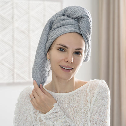 Woman wearing a gray muslin towel wrapped around her hair; one towel is sold.