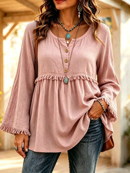 Dusty pink blouse on a model, front view with three-button neckline, gathered body and fringe trim across the chest and sleeve ends.