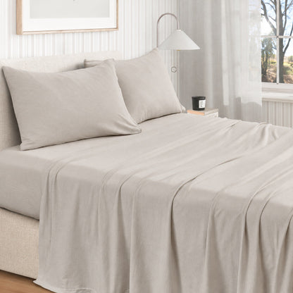 Sand cotton jersey knit sheet set shown on a made bed from a second room angle, with matching pillows and draped sheet.