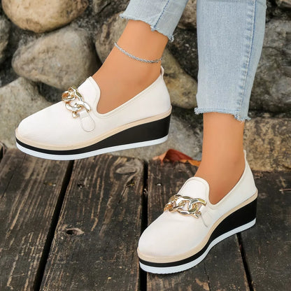 Beige round-toe wedge loafers viewed from the side while worn.