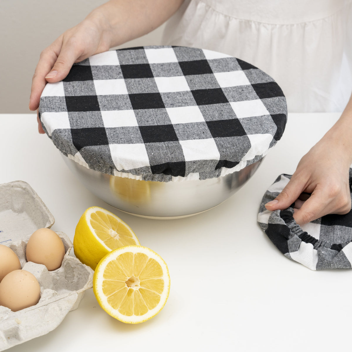Black and white checked elastic cover being fitted over a bowl