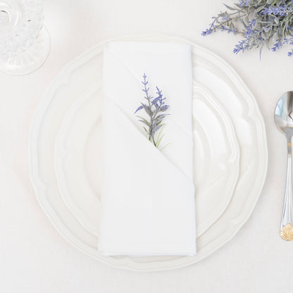 White flour-sack cotton napkin folded on a dinner plate with floral styling