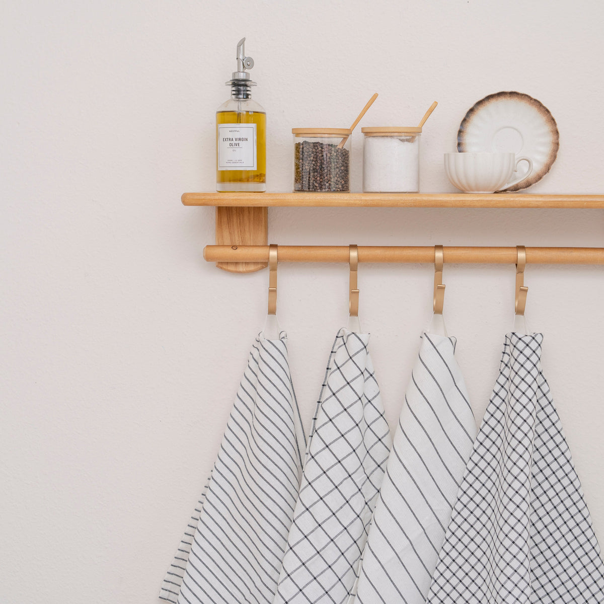 Black-and-white striped and checked cotton kitchen towels hanging from a kitchen shelf; styling accessories excluded