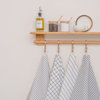 Black-and-white striped and checked cotton kitchen towels hanging from a kitchen shelf; styling accessories excluded