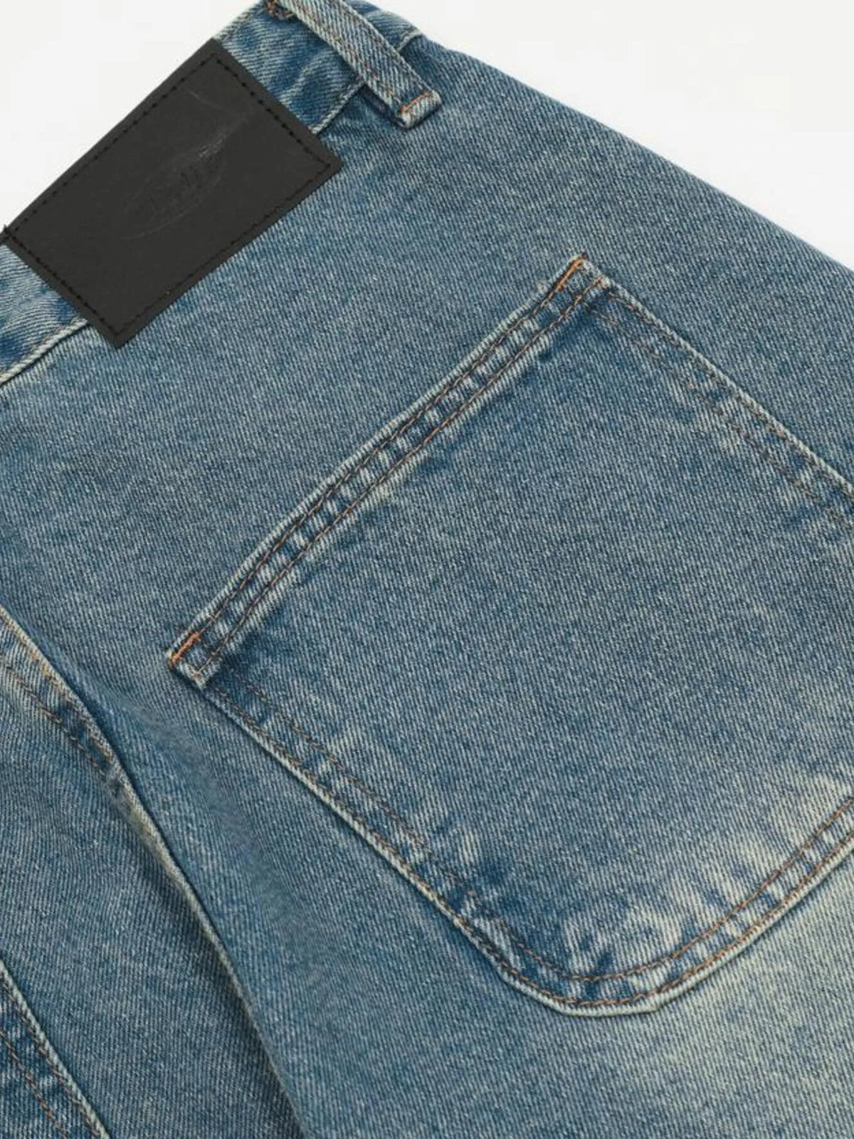 Close-up of a rear patch pocket and dark waistband patch on the blue cargo jeans.