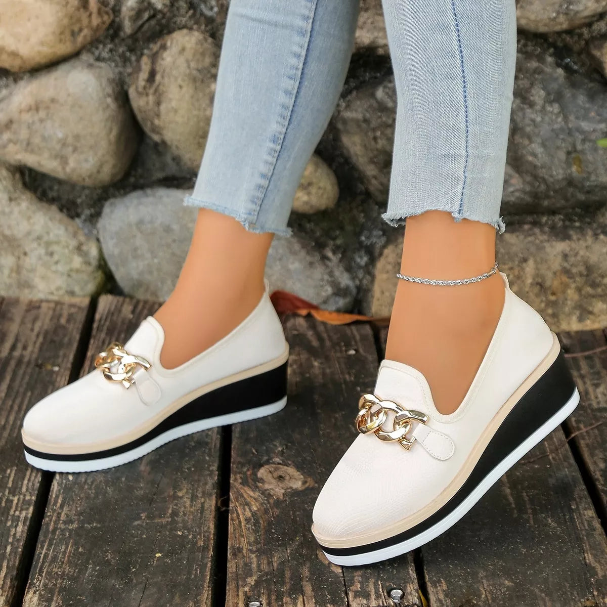 Side view of beige slip-on wedge loafers with chain-style trim; trousers and ankle jewellery are not included.