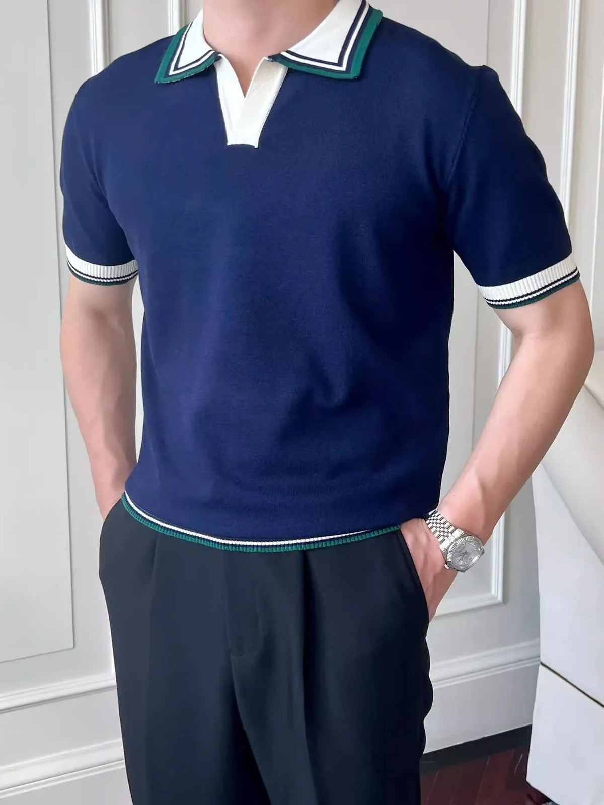 Front view of the Royal Blue knit polo with white and green striped trim. Trousers and watch are styling accessories.