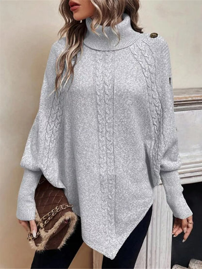 Light gray cable-knit turtleneck cape sweater. Front three-quarter view, model in black pants. Styling accessories are not included.